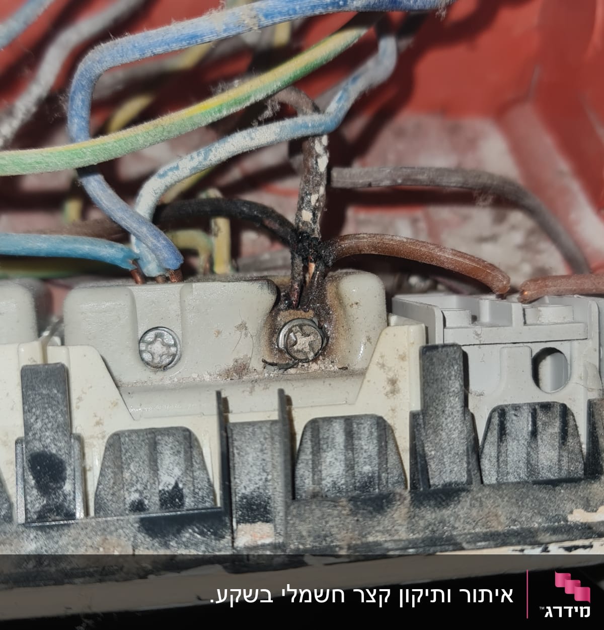 חוטי חשמל צבעוניים מחוברים לקופסת חיבורים עם סימני שריפה